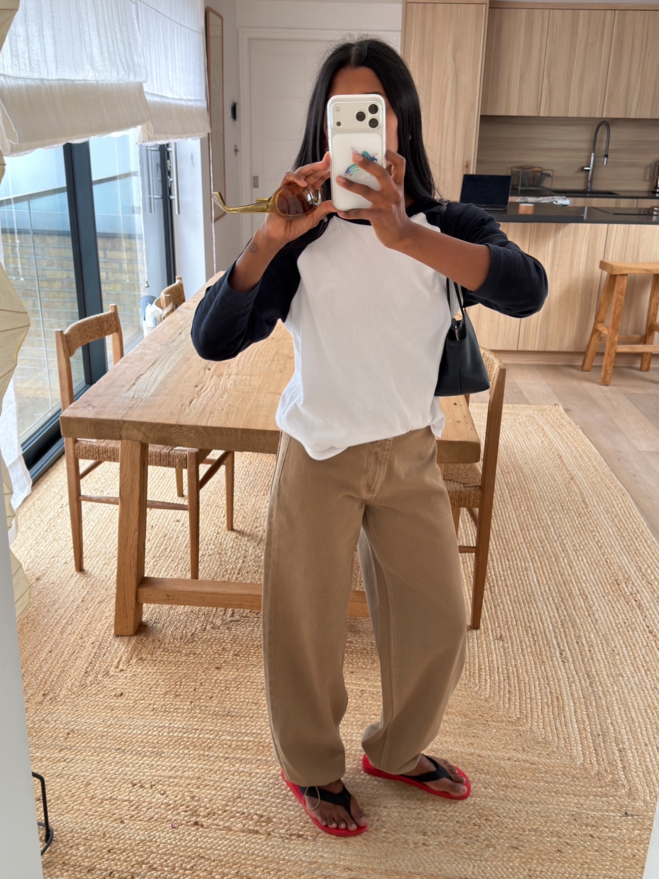 An image of @monikh wearing khaki trousers with a raglan top and red-and-black flip-flops.