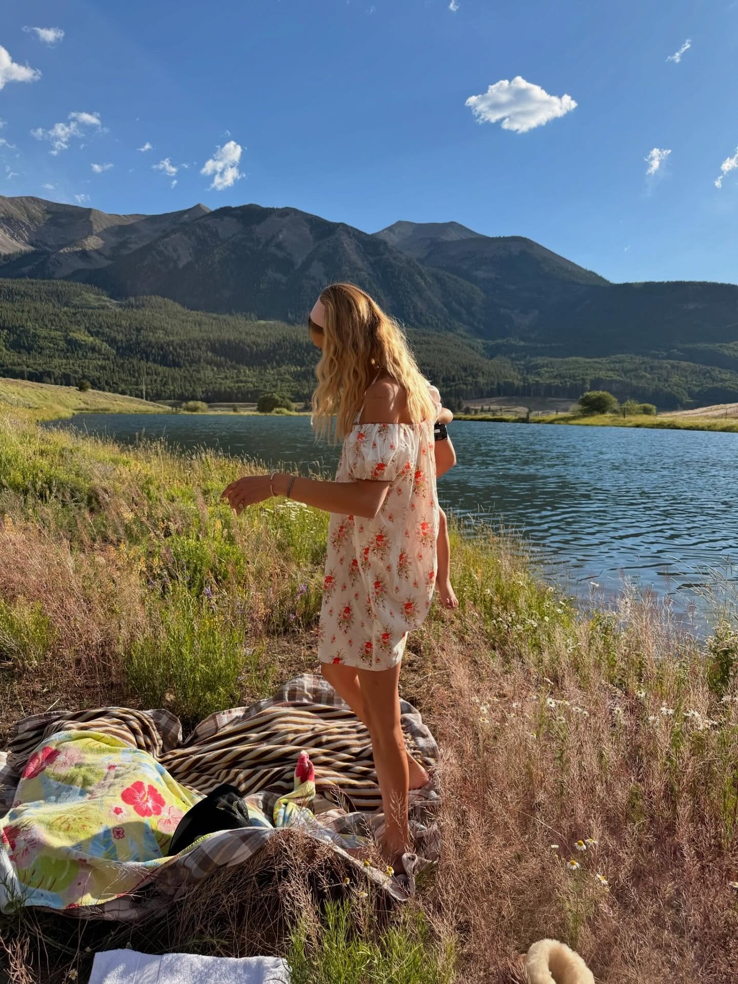 Bella Hadid wears a cotton floral dress outside by a lake.
