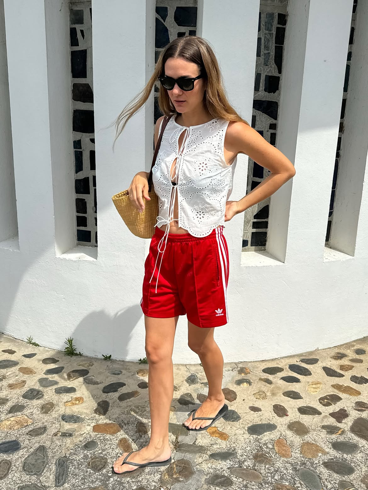 Anne Laure-Mais wearing red Adidas track shorts with an eyelet Matteau white top.