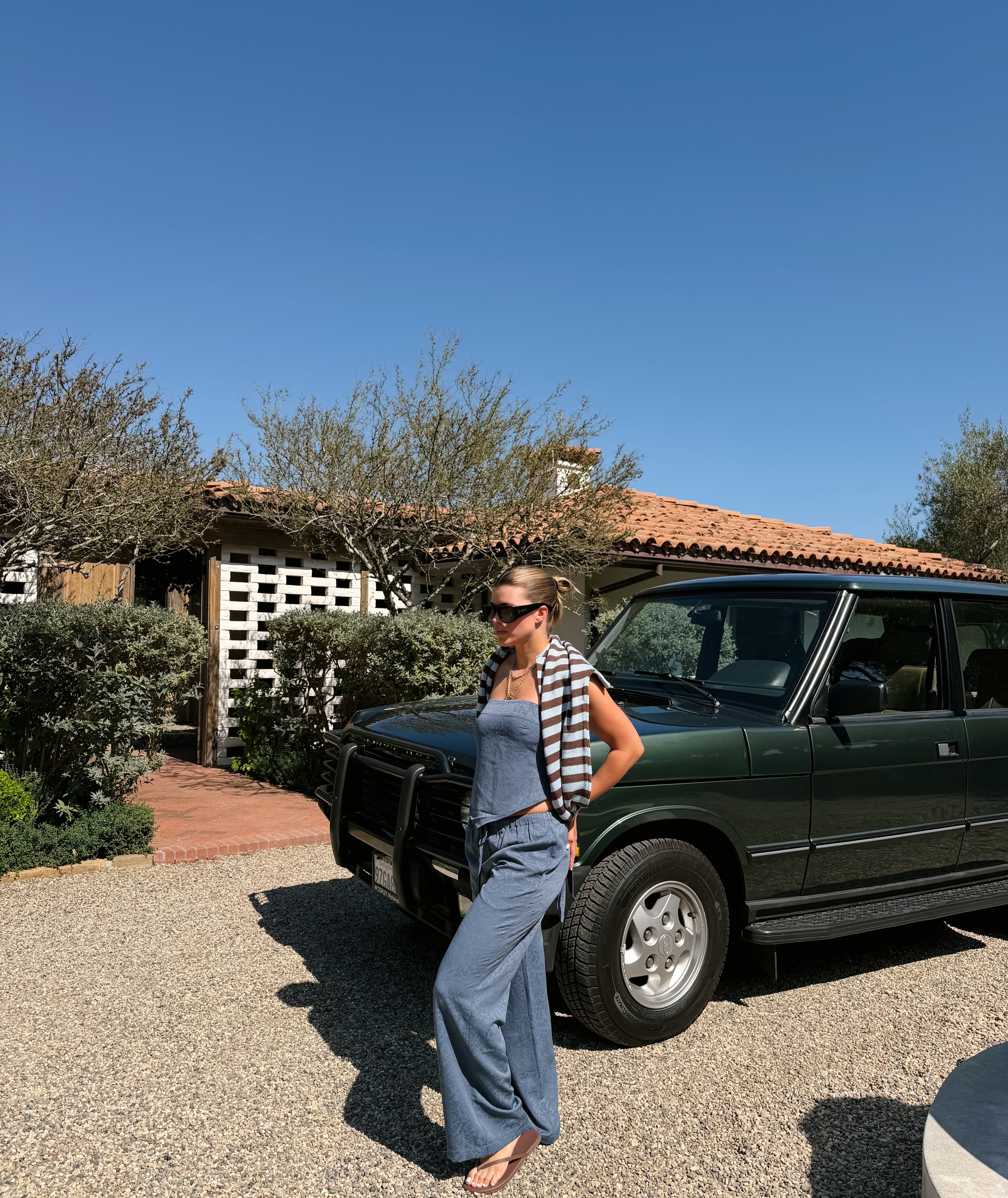 sofia wears a blue strapless top, blue jacquard drawstring pants, brown flip-flops and a stripe sweater.