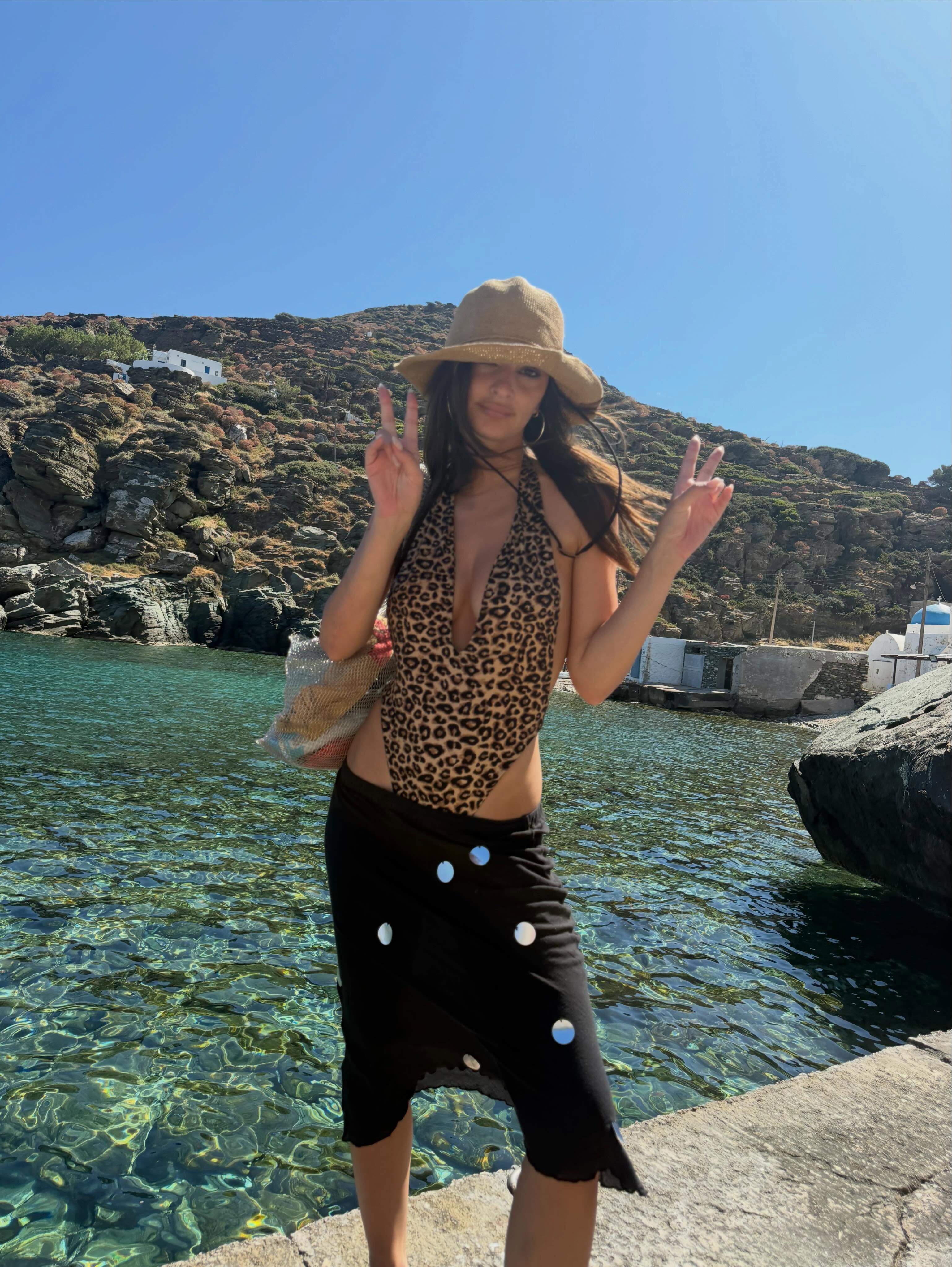 emily ratajkowski wears a swimsuit, sarong and raffia hat for summer fashion trends 2026