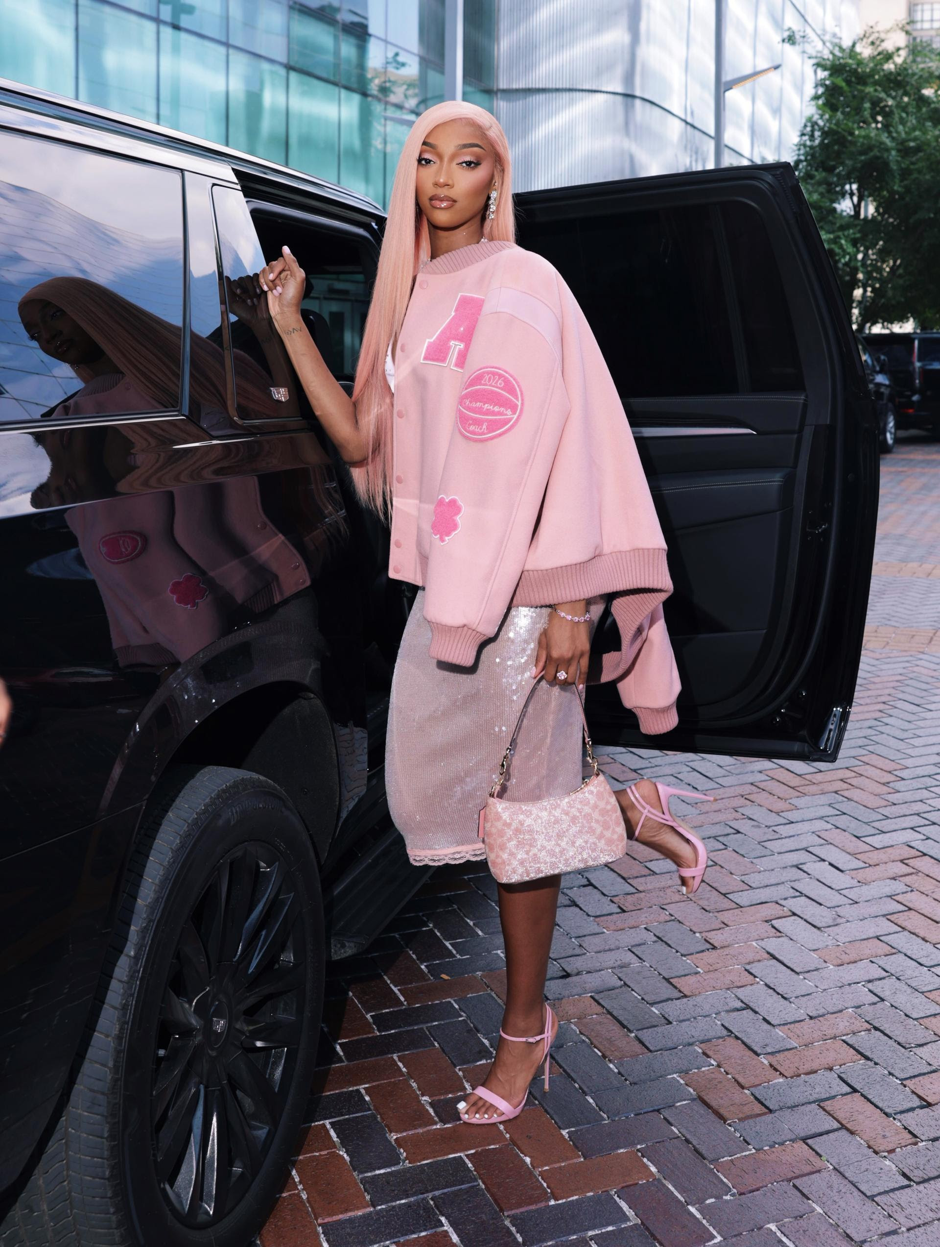 Angel Reese wearing a pink custom Coach varsity jacket with a sequin dress in Chicago during WNBA All-Star weekend.