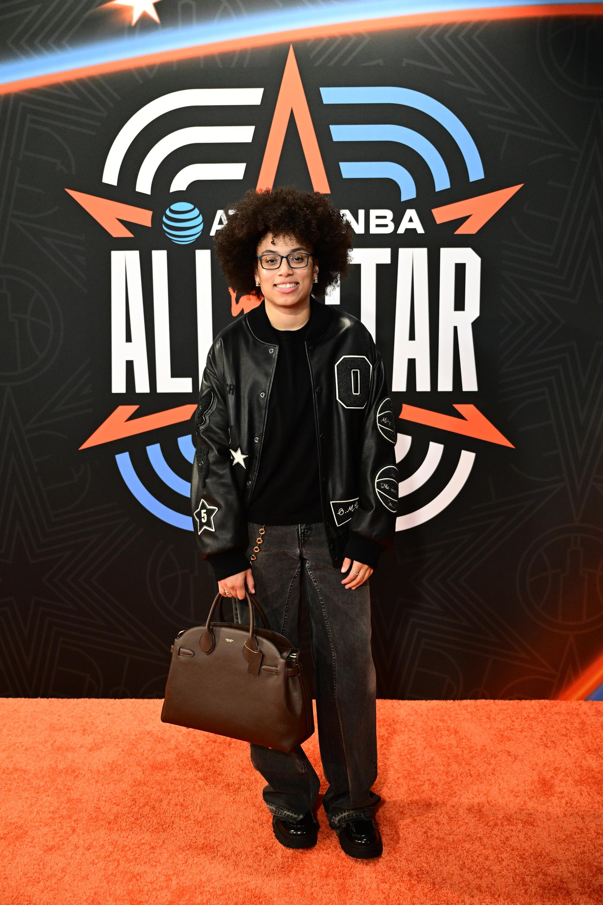 Olivia Miles wearing a black custom Coach varsity jacket with a black jeans in Chicago during WNBA All-Star weekend.