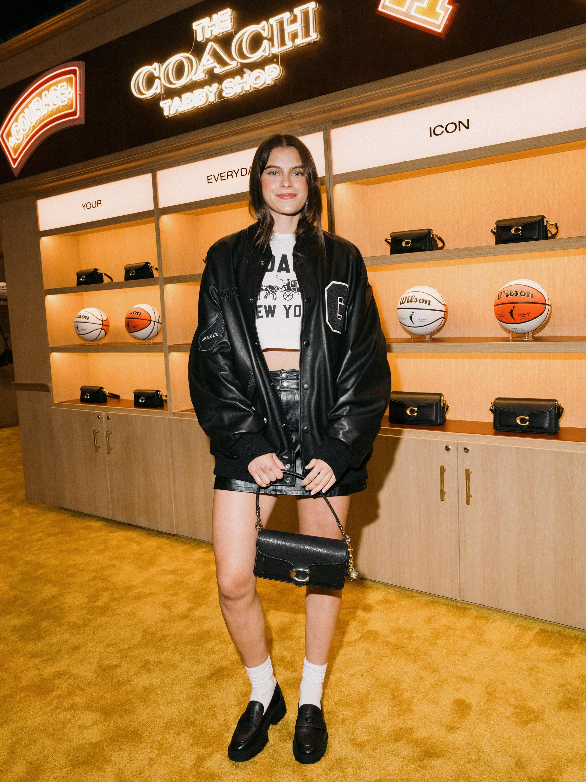 Gabriela Jacquez wearing a black custom Coach varsity jacket with a leather miniskirt in Chicago during WNBA All-Star weekend.