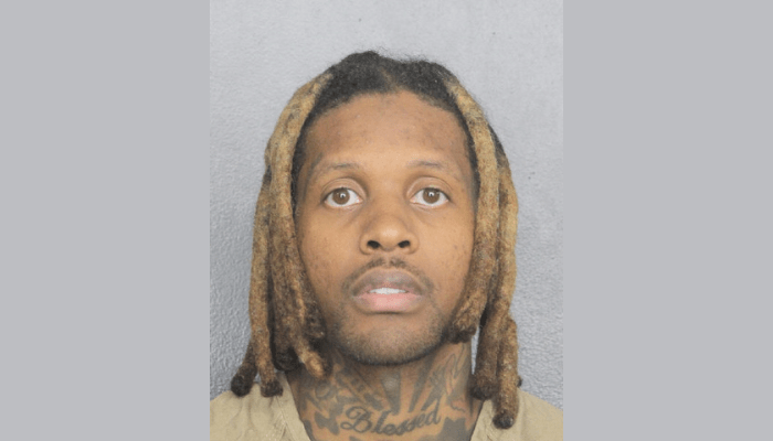 Portrait of a man with dreadlocks and a facial tattoo.